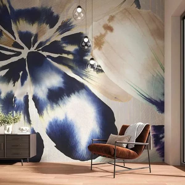 Tecnografica room with a large blue and cream abstract floral wallcovering mural, a rust velvet armchair and glass pendant lights