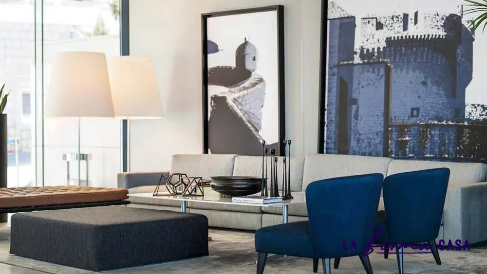 Pale rug with blue armchairs by a city window by Warli in Canada