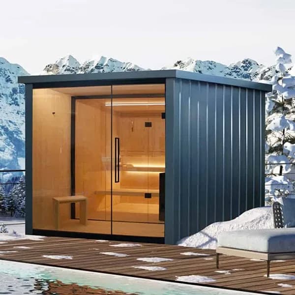 Megius Spa outdoor sauna cabin with a full-height glass front and warm wood interior, on a snowy deck beside a pool with mountains behind