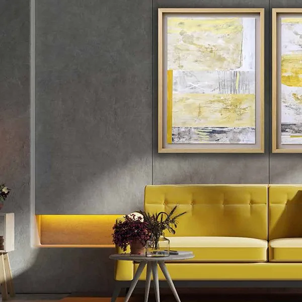 Novocuadro pair of framed yellow and grey abstract paintings on a dark plaster wall above a buttoned yellow sofa