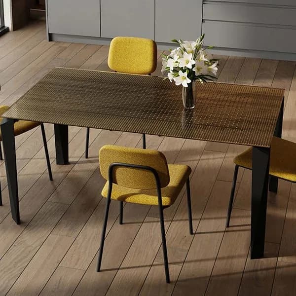 Zamagna dining table with a bronze textured glass top on black legs, surrounded by mustard bouclé chairs on black frames on an oak floor